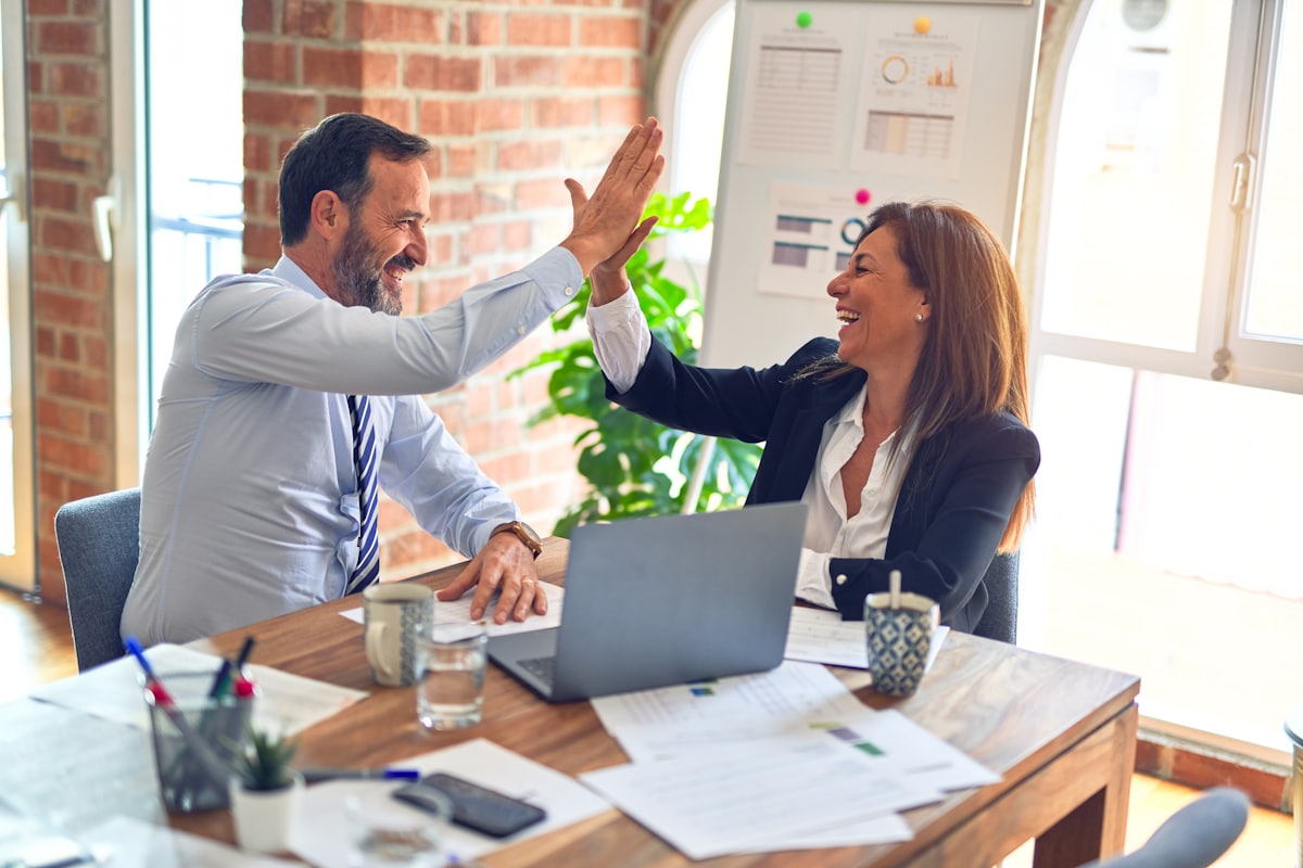 A consultant and a client celebrating an approved visa application at the office